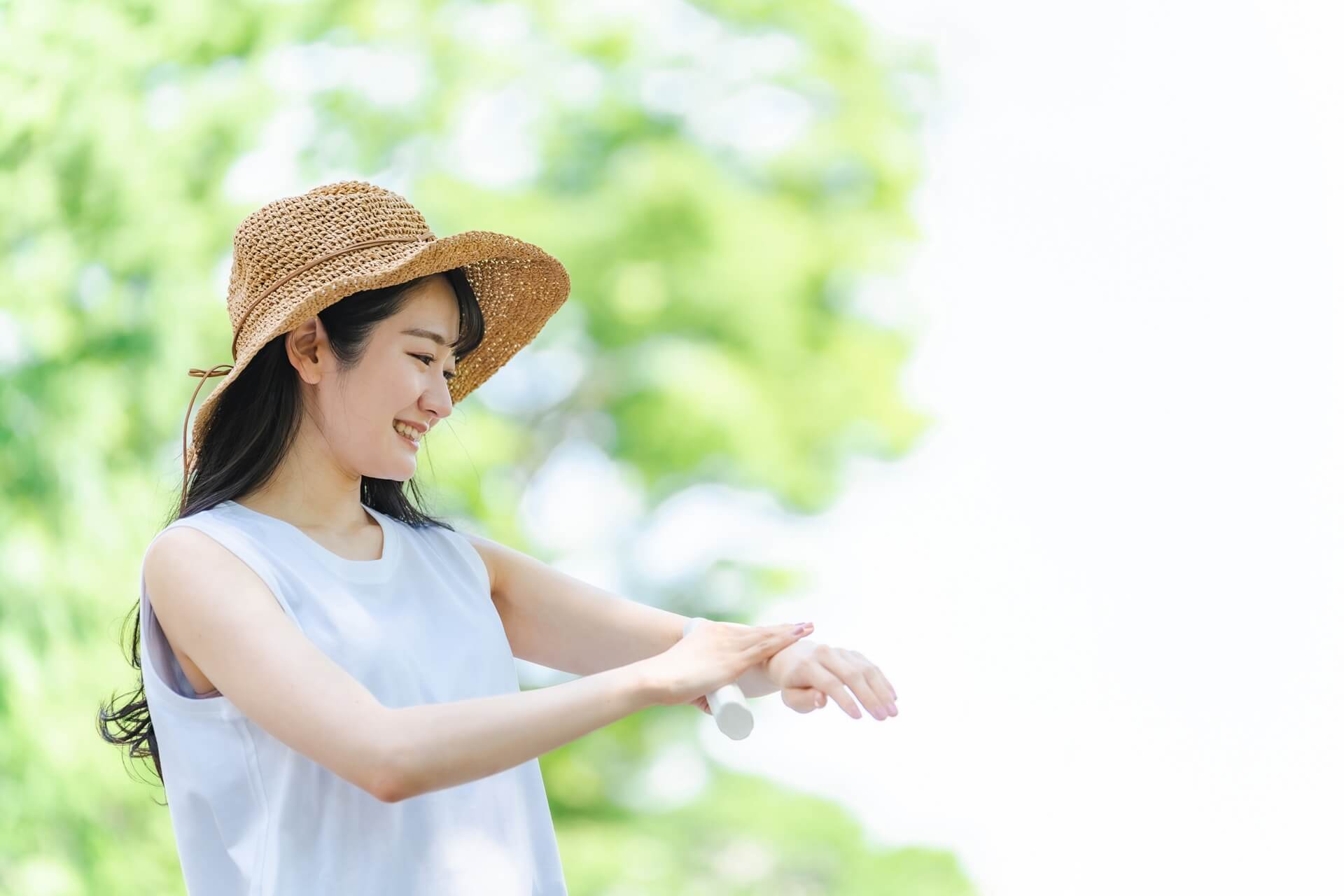 日焼け止めを塗る麦わら帽子の女性